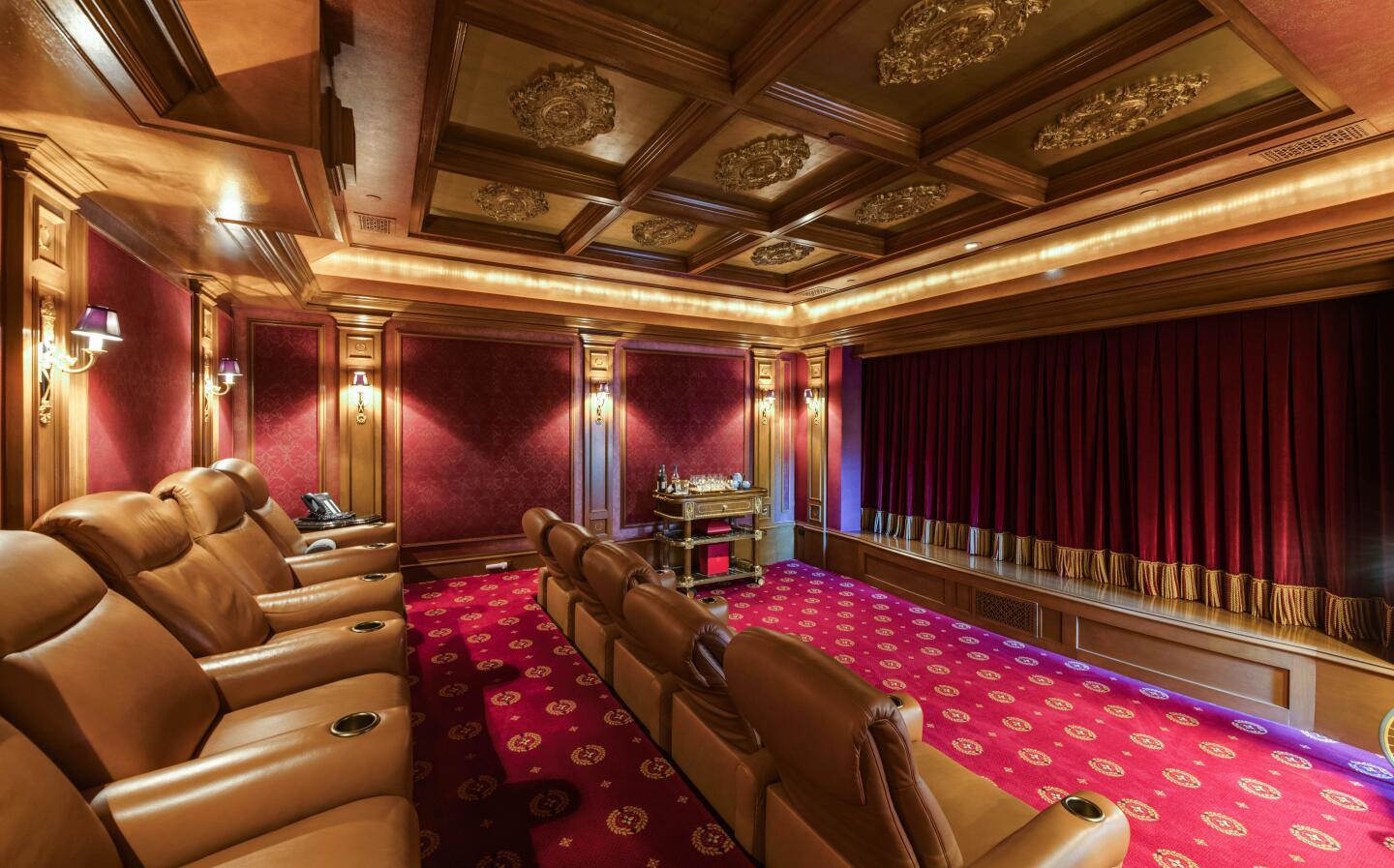 The carpeted movie theater with leather recliners an decorative panels on the ceiling.