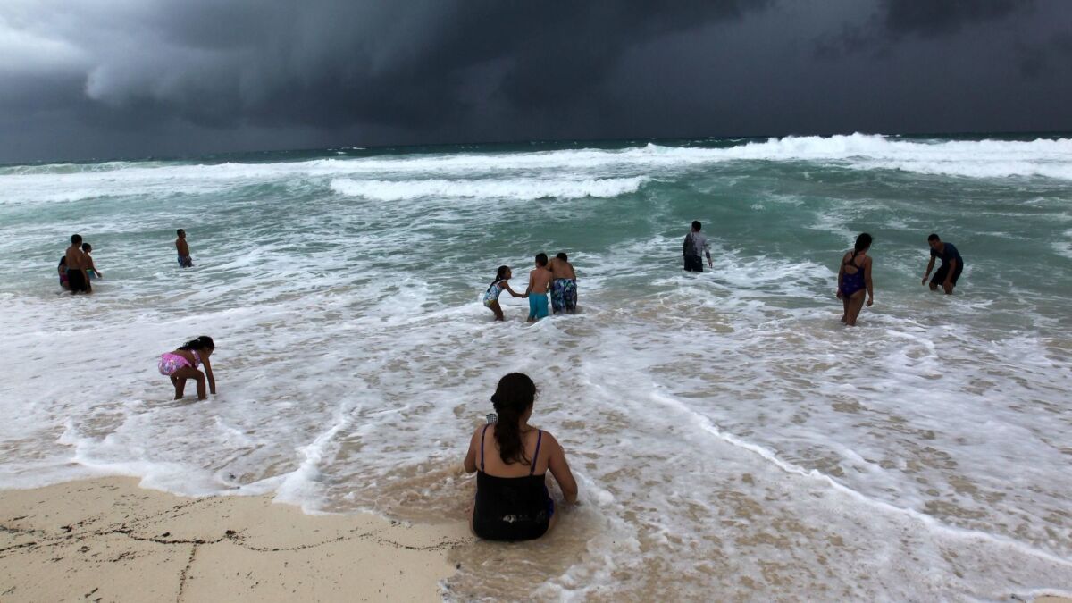 People swim in the turbulent sea in Cancun, Mexico, on Sunday, as a tropical depression that was moving toward Florida was upgraded to a named tropical storm, Michael.