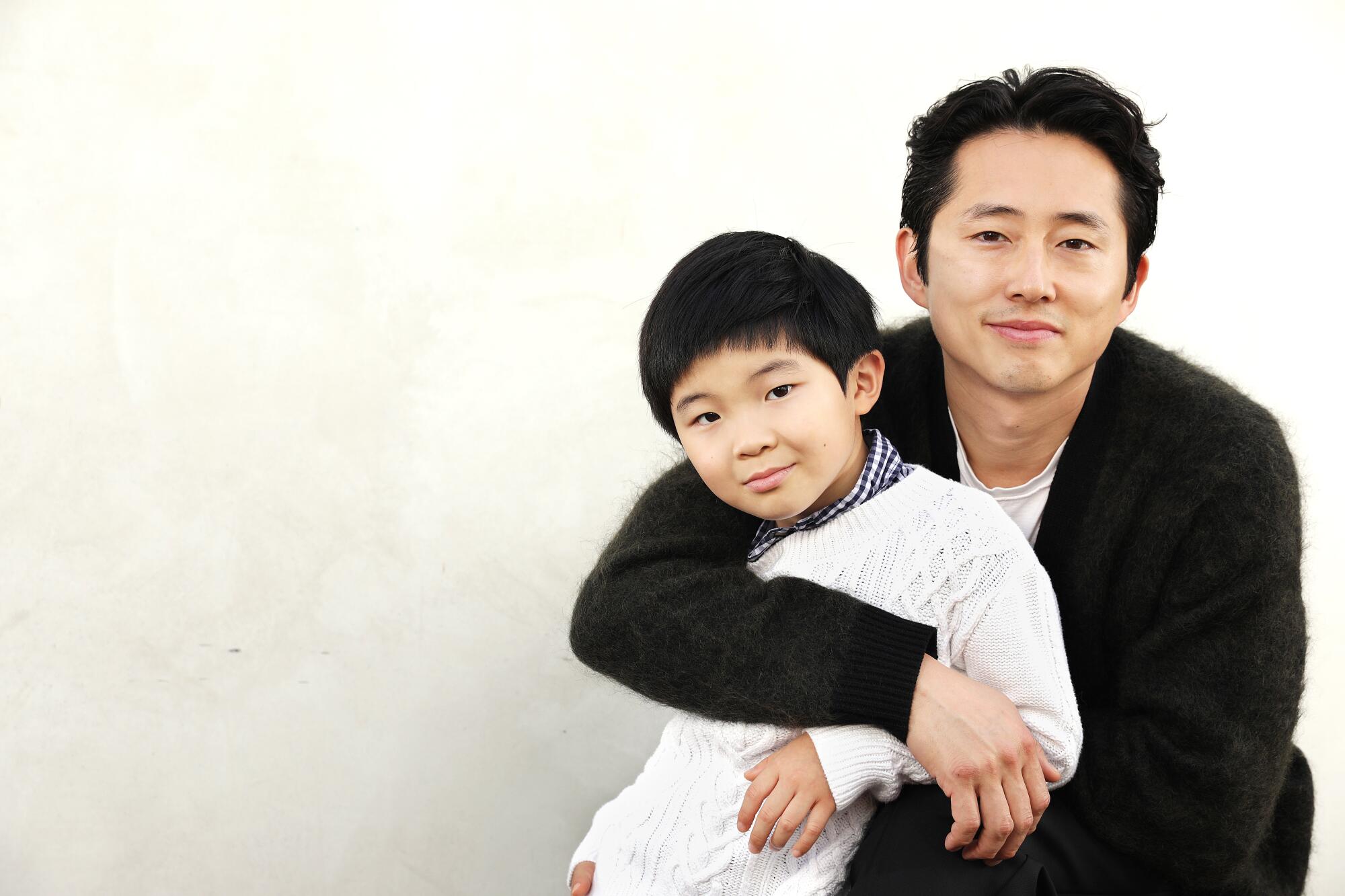 Actor Steven Yeun embraces Alan Kim, who plays his son in "Minari."