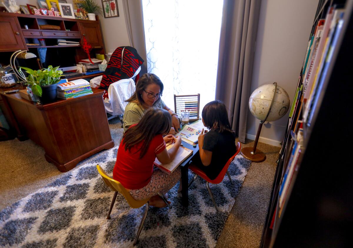 Maggie Tamayo works with daughters Esperanza, 8 and Amelia, 6, on home school assignments.