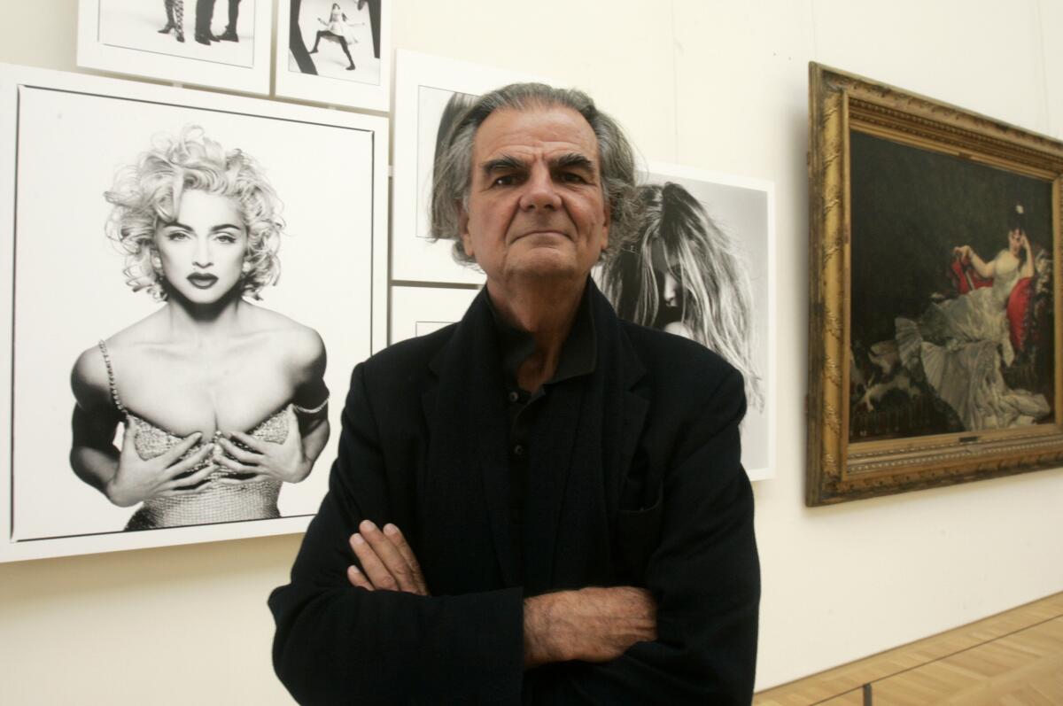 Photographer Patrick Demarchelier appears in front of his photograph of Madonna at the Petit Palais in Paris, Sept. 26, 2008. Demarchelier, the French-born photographer known for his high fashion images of top models and celebrities, including Princess Diana, has died at age 78. (AP Photo/Michel Euler, File)
