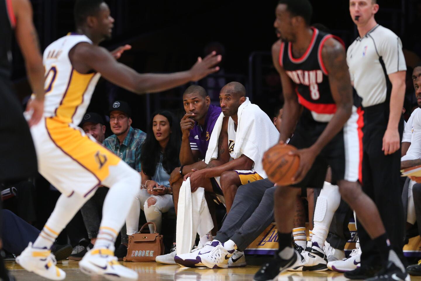 Lakers veterans Kobe Bryant and Metta World Peace watch the action from the bench in the waning moments of a 107-93 loss to the Trail Blazers.