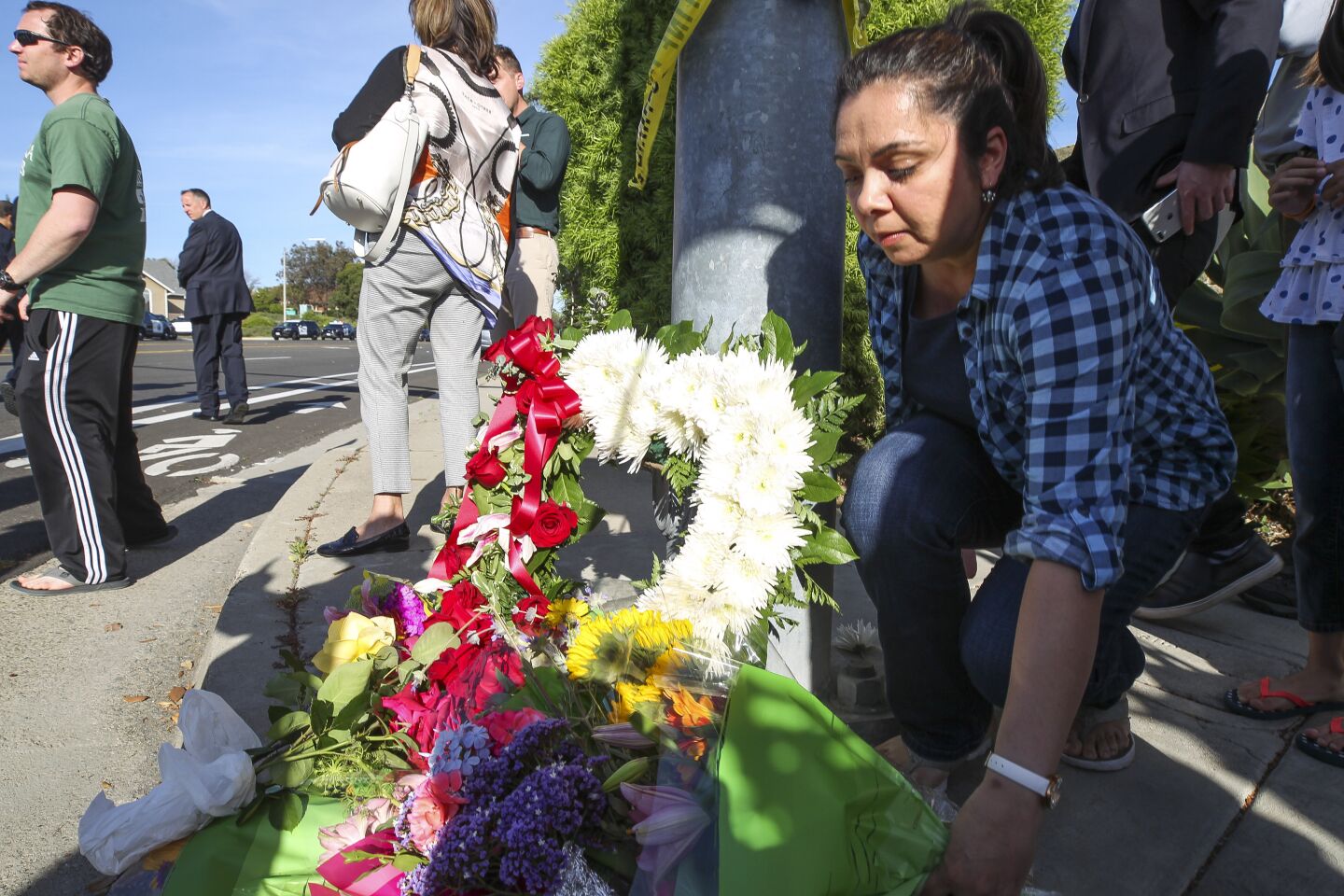 A woman leaves flowers at small memorial near Chabad of Poway, where a man with a gun shot multiple people inside the synagogue, killing one, in Poway on Saturday, April 27, 2019 in Poway, California.