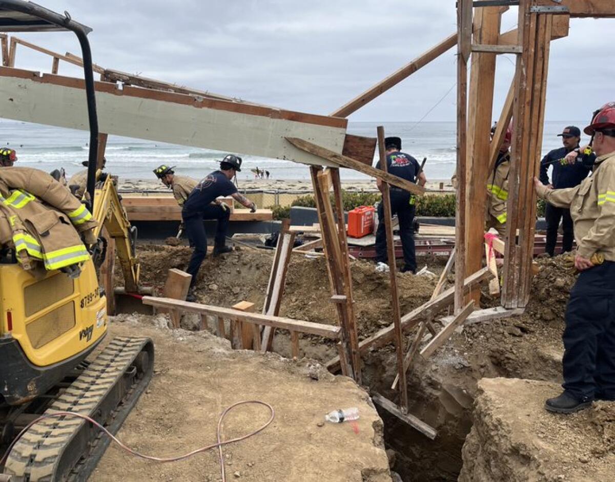 San Diego fire crews work to rescue a man trapped a in trench in La Jolla Shores,