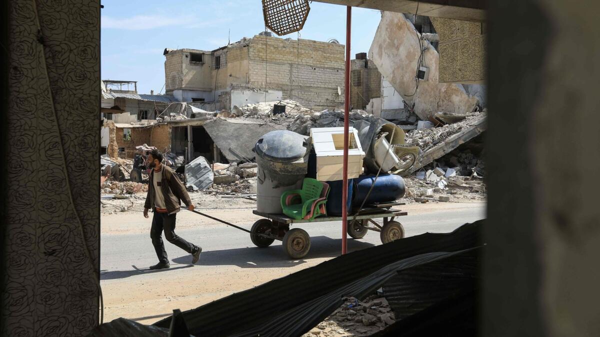 A Syrian man pulls a wagon filled with belongings as he flees his home in Douma.