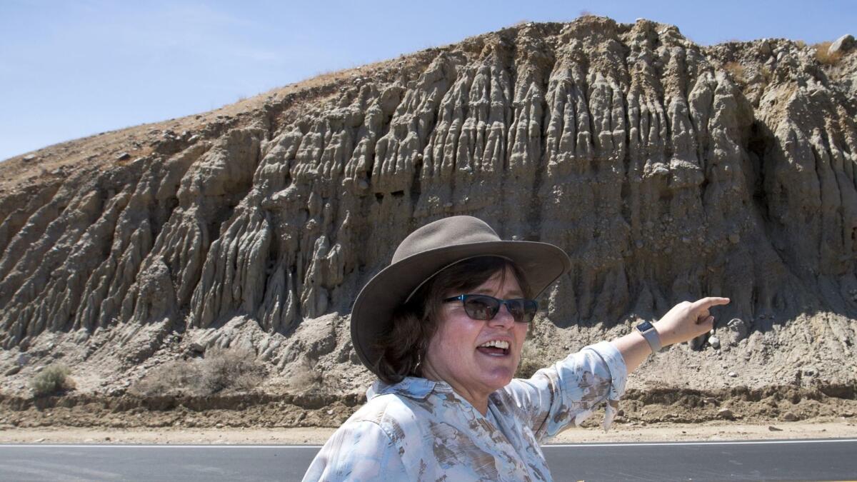 Seismologist Lucy Jones, center, stands directly on the San Andreas fault and points to an area of the hillside where the rocks abruptly change â a sign of where the fault is located.