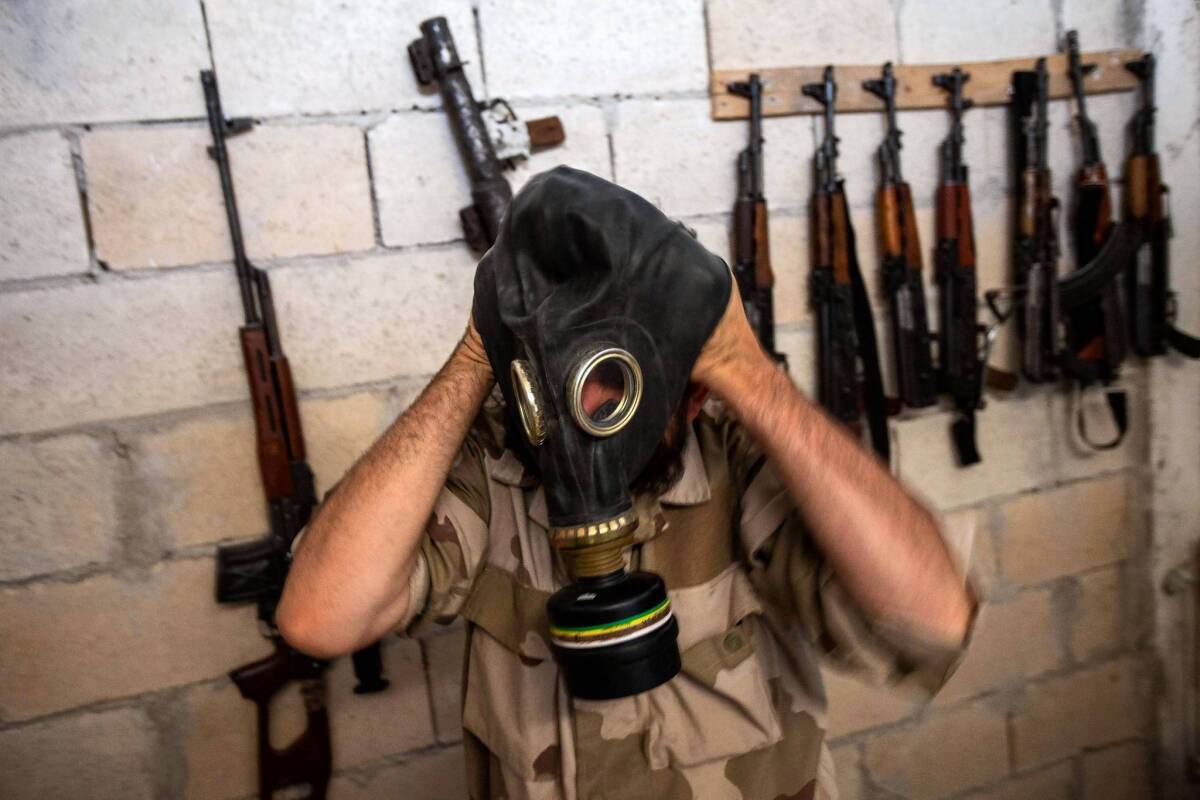 A Syrian rebels tries on a gas mask seized from a Syrian army factory. When the U.S. does deliver its promised weapons to the opposition forces, they are expected to be small arms, not the anti-tank and antiaircraft weaponry the rebels seek.