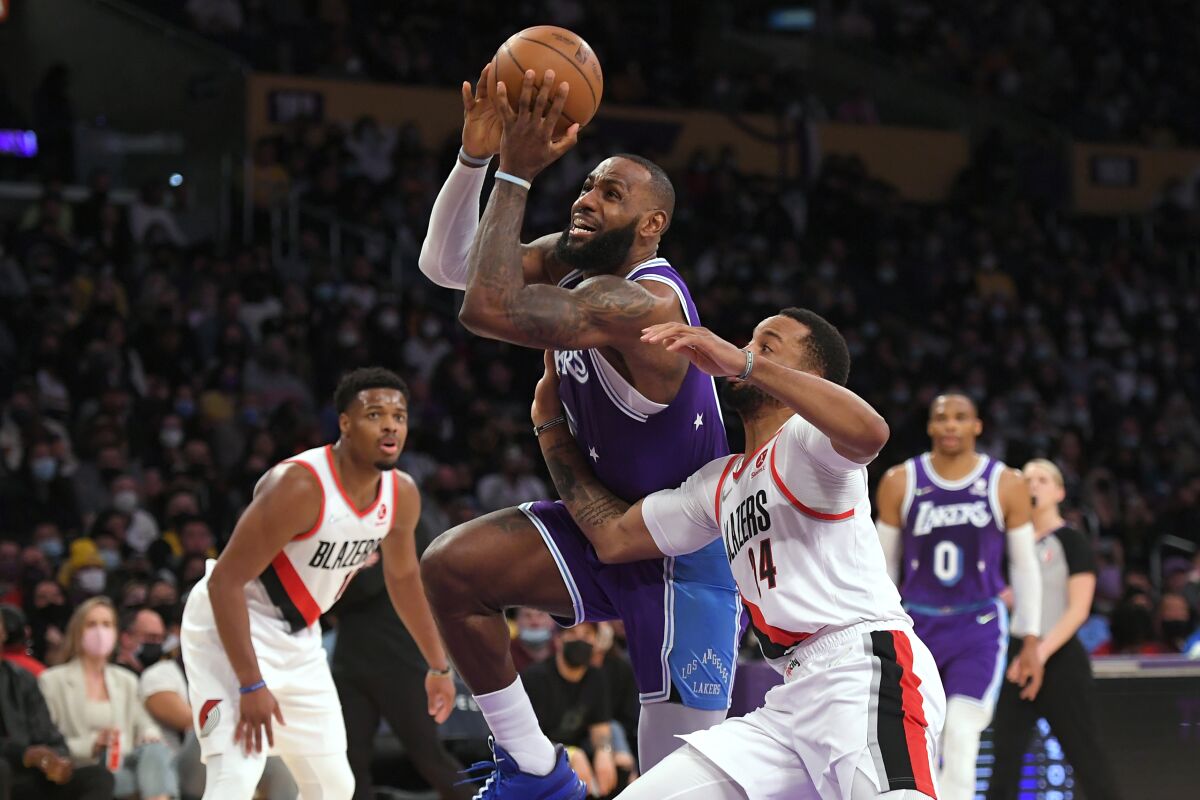 Lakers star LeBron James drives past Portland Trail Blazers forward Norman Powell during the first half Friday.