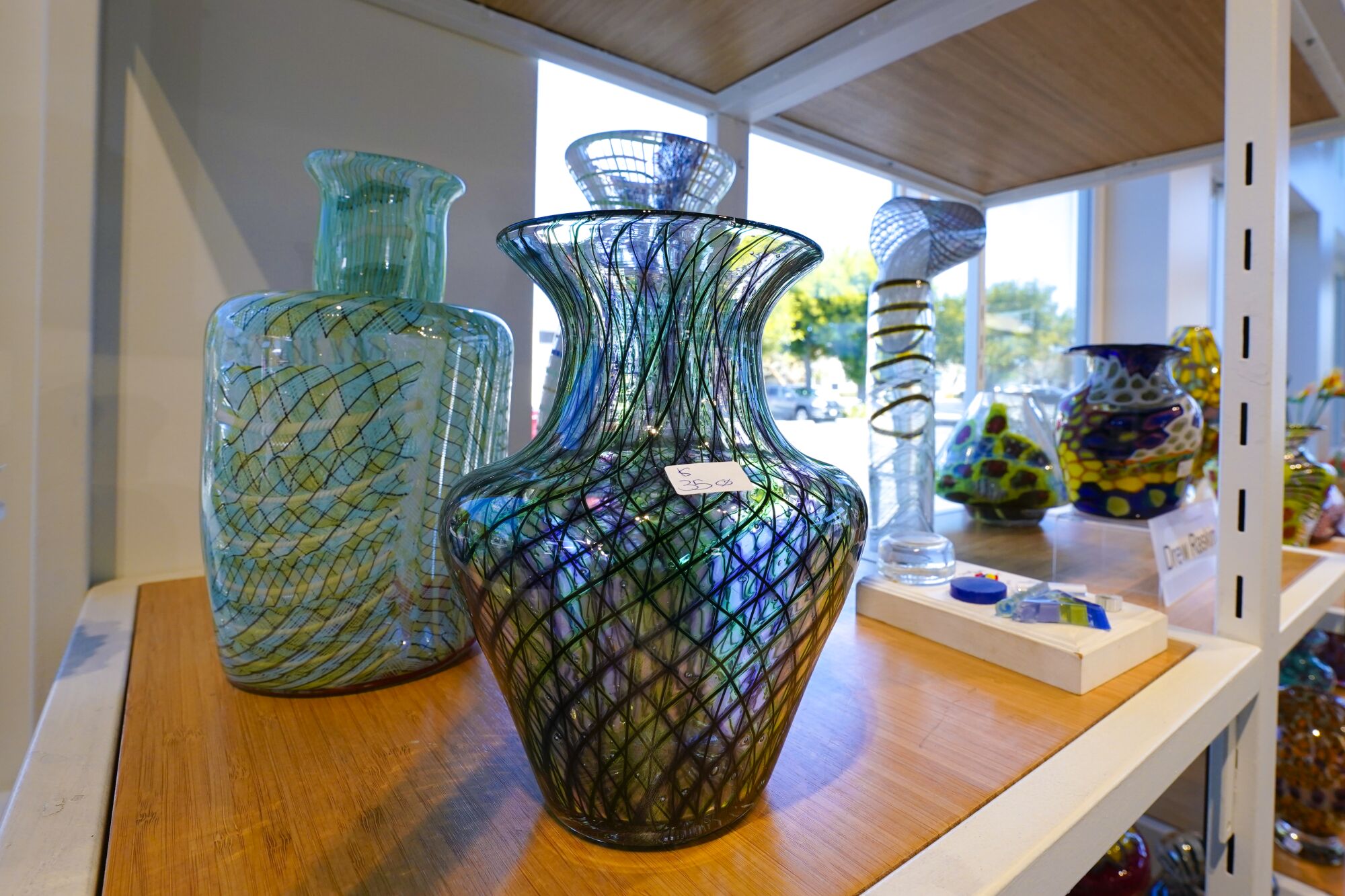 A display shelf holds the glass art of one of the gallery owners, Drew Raskin.