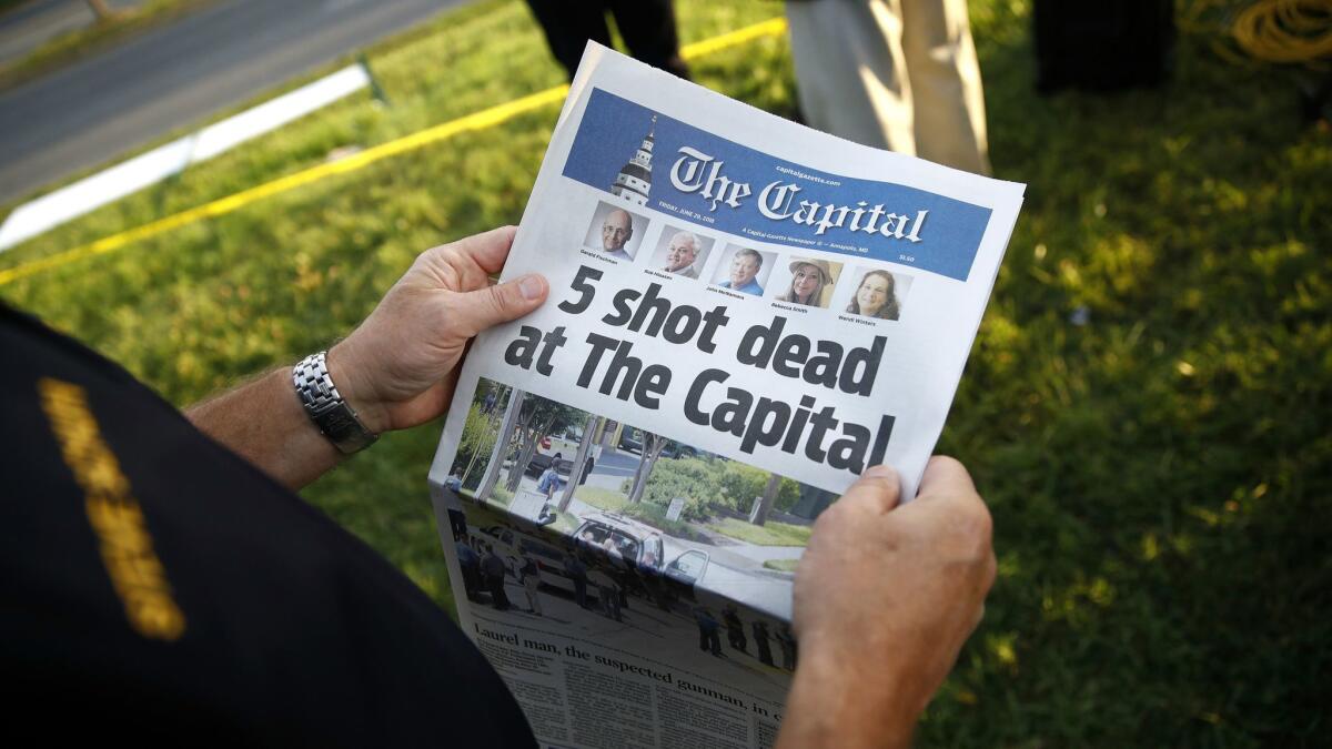 Steve Schuh, county executive of Anne Arundel County, holds a copy of Friday's edition of the Capital near the scene of a shooting at the newspaper's office.