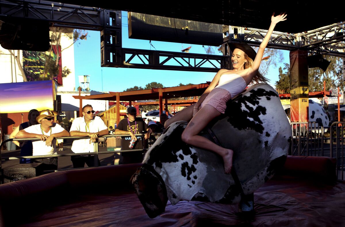 Ashlyn Ballou, 18, of Rancho Cucamonga, tries to keep her balance while riding a mechanical bull at the Los Angeles County Fair in Pomona. Attendance dropped this year to 1.2 million, compared to 1.4 million last year.