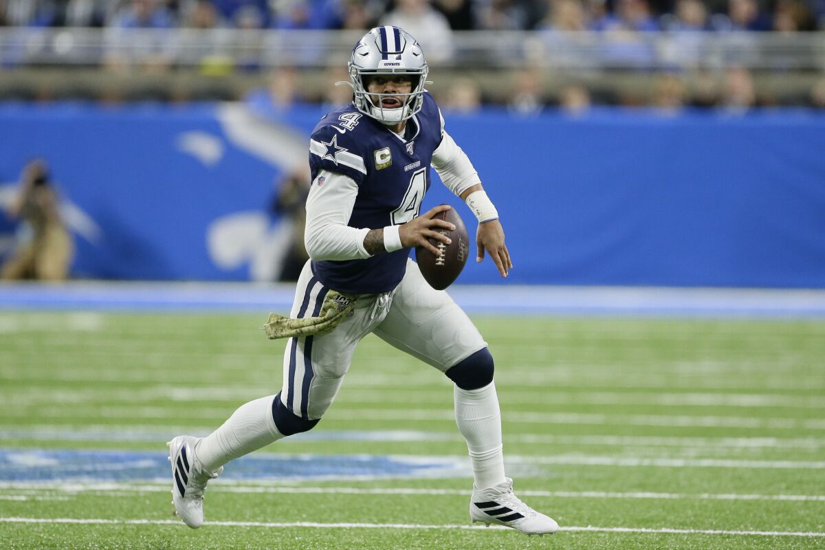 Cowboys quarterback Dak Prescott rolls out while looking for a receiver during a game against the Lions. 