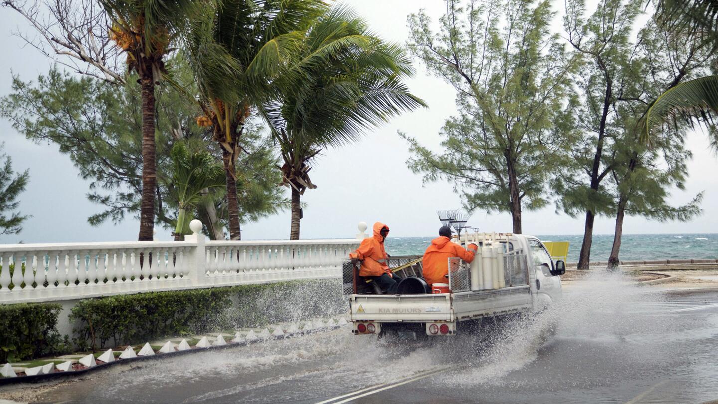 Landscapers ride in a truck along a stretch of road that's partially flooded from rain triggered by the arrival of Hurricane Matthew, in the eastern district of Nassau, Bahamas, on Oct. 5, 2016.