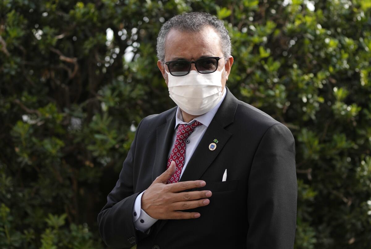 Tedros Adhanom Ghebreyesus arrives for a meeting in a suit and face mask.