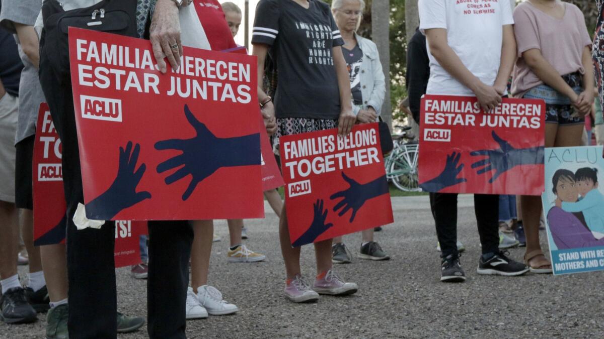 People hold signs that read "families belong together" in English and Spanish during a vigil June 30 at Alice Hope Wilson Park in Brownsville, Texas, to advocate against the separation of migrant families at the U.S.-Mexico border.