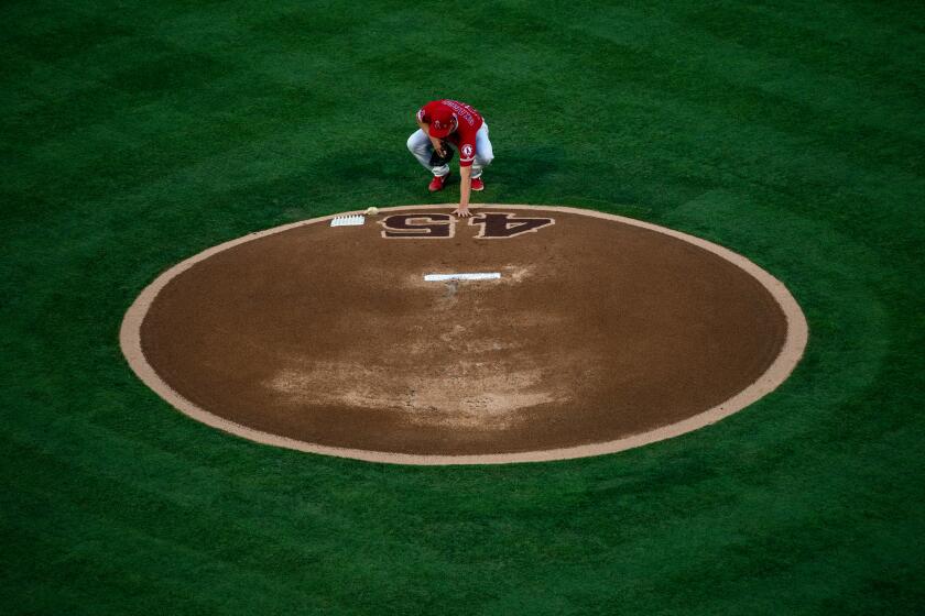 ANAHEIM, CALIF. - JULY 12: Los Angeles Angels starting pitcher Taylor Cole (67) places his hand on the Number 45 on the pitchers mound, in memory of the late Tyler Skaggs before the start of a Major League Baseball game between the Los Angeles Angels and the Seattle Mariners at Angel Stadium on Friday, July 12, 2019 in Anaheim, Calif. (Kent Nishimura / Los Angeles Times)