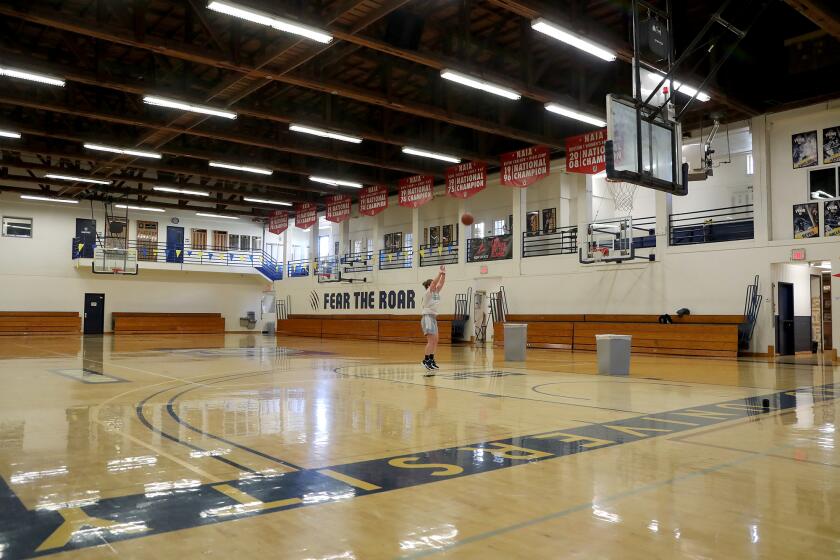 Lauren Baumgartner, a junior who plays point guard for the girlsO basketball team, gets some shots up as she trains on Tuesday at Vanguard UniversityOs gymnasium. The university is replacing its old gym, nicknamed The Pit, with the new Lions Arena.
