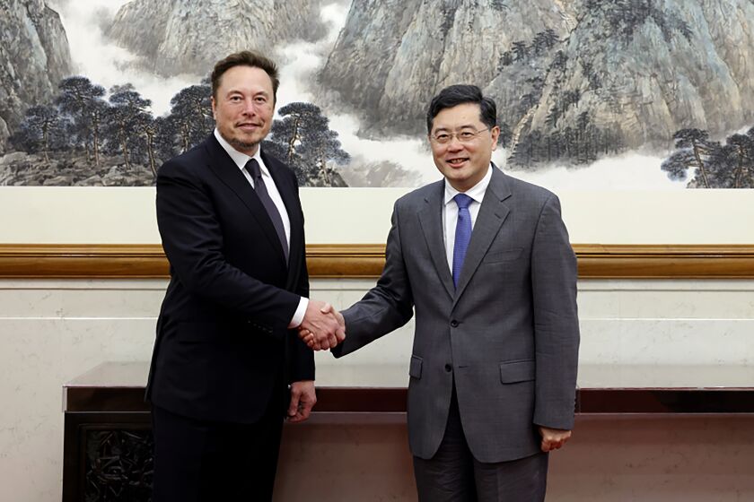 In this photo taken Tuesday, May 30 2023 and released by Ministry of Foreign Affairs of the People's Republic of China, China's Foreign Minister Qin Gang, right, poses for photos with Tesla Ltd. CEO Elon Musk in Beijing. China’s foreign minister met Tesla Ltd. CEO Elon Musk on Tuesday and said strained U.S.-Chinese relations require “mutual respect,” while delivering a message of reassurance that foreign companies are welcome. (Ministry of Foreign Affairs of the People's Republic of China via AP)