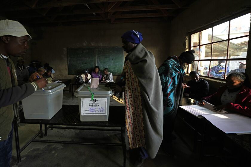 A man wearing a blanket cast his vote at a poling station in Maseru, South Africa, Friday, Oct. 7, 2022. Voters across Lesotho are heading to the polls Friday to elect a leader to find solutions to high unemployment and crime. (AP Photo/Themba Hadebe)
