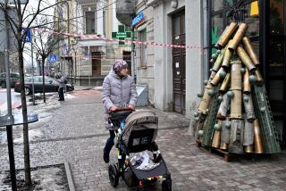A woman pushes a pram as she walks past a symbolic Christmas tree made from spent shells casing and other spent ammunition erected outside a cafe in the center of Kyiv on December 18, 2023, amid Russian invasion in Ukraine. (Photo by Sergei SUPINSKY / AFP) (Photo by SERGEI SUPINSKY/AFP via Getty Images)