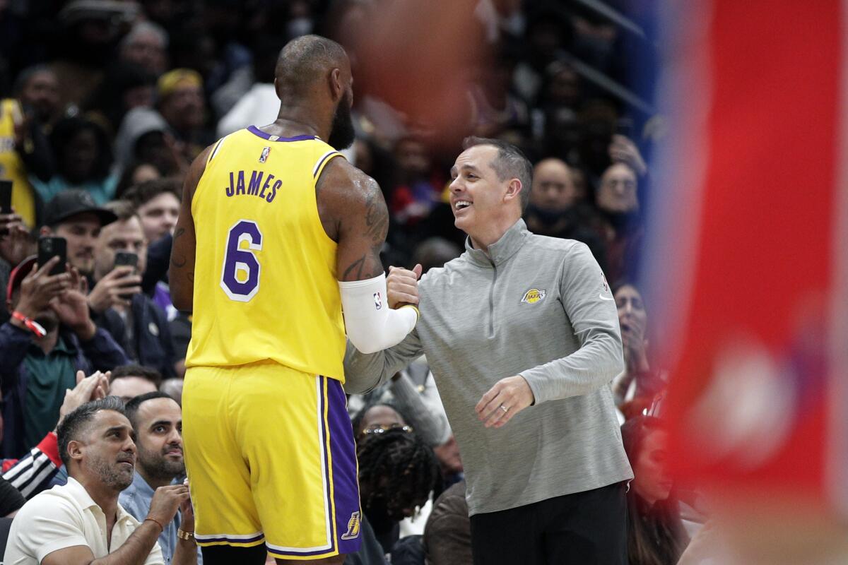 The Lakers' LeBron James is congratulated by coach Frank Vogel after moving into second place on the career scoring list.