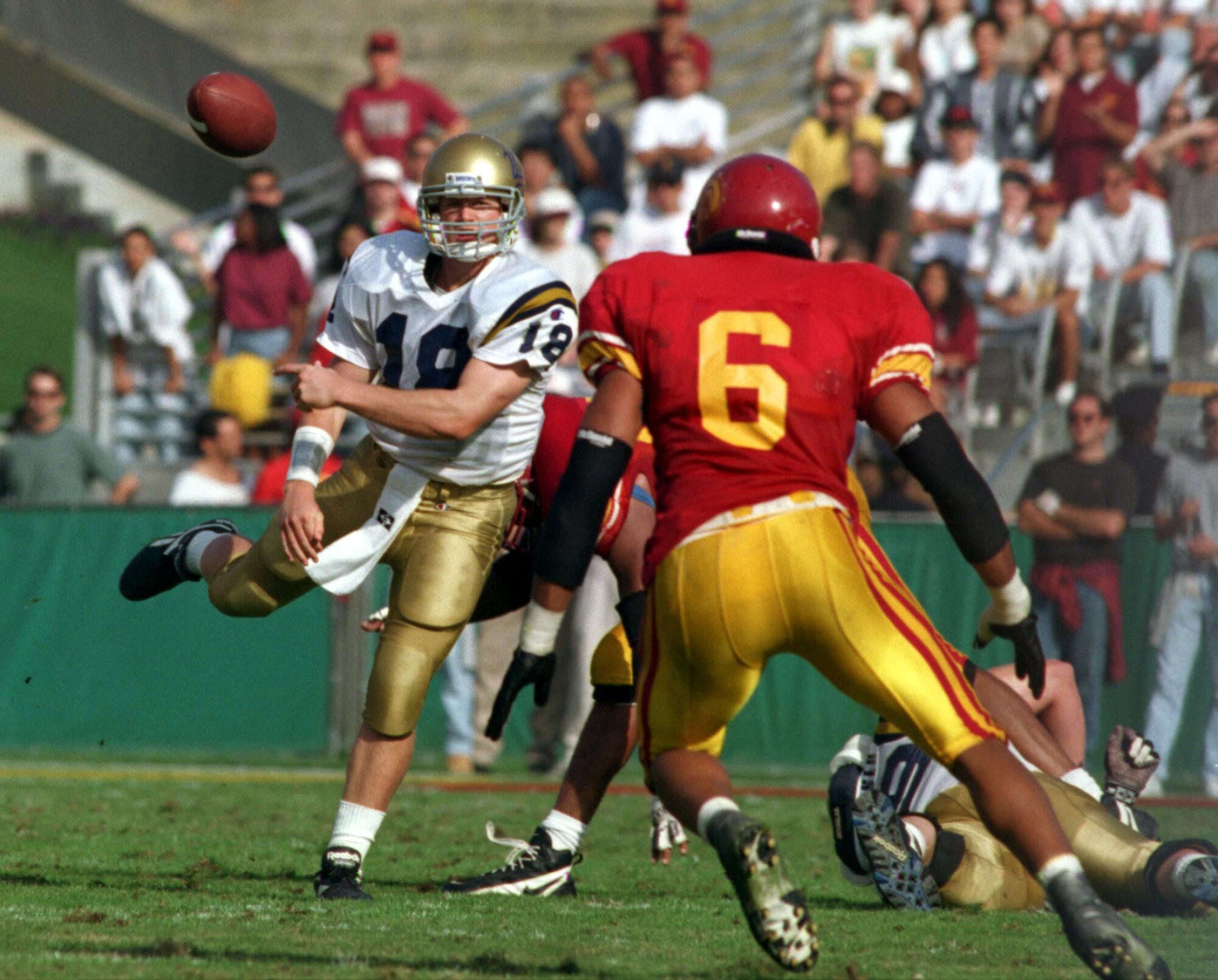 1997 年，加州大学洛杉矶分校 (UCLA) 四分卫凯德·麦克诺 (Cade McNown) 在对阵竞争对手南加州大学 (USC) 的比赛中试图摆脱防守球员。