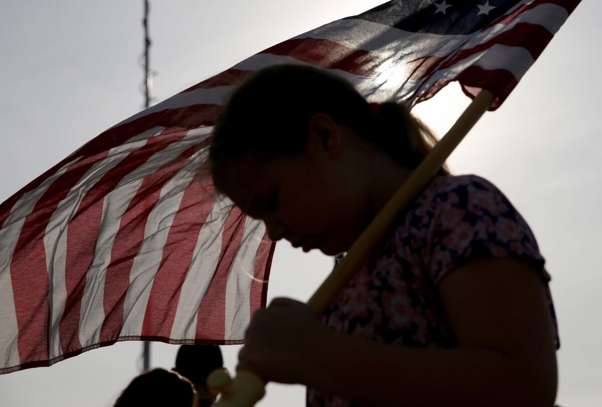 Jenna Ryan, 11, holds a flag as she participated Friday in a flag walk in memory of those killed and injured on the Ft. Hood Army post this week.