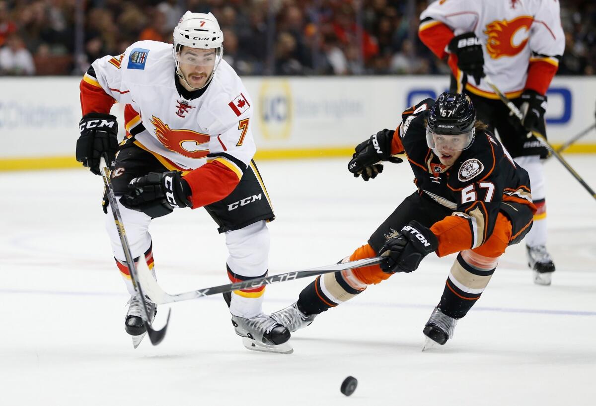 The Ducks' Rickard Rakell, right, battles Calgary's T.J. Brodie for a loose puck Tuesday night.