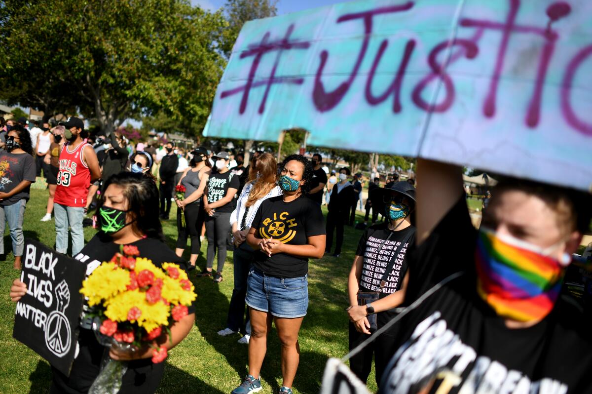 People in a park with signs that read Black Lives Matter and Justice