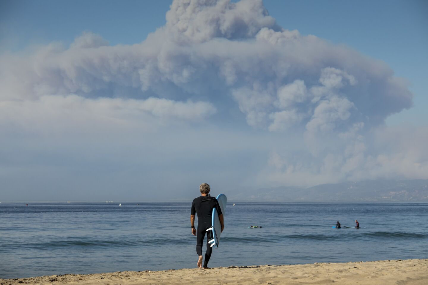 Michael Quane of El Segundo came to the El Porto area of Manhattan Beach to surf against the backdrop of billowing smoke from the Woolsey fire over Santa Monica.