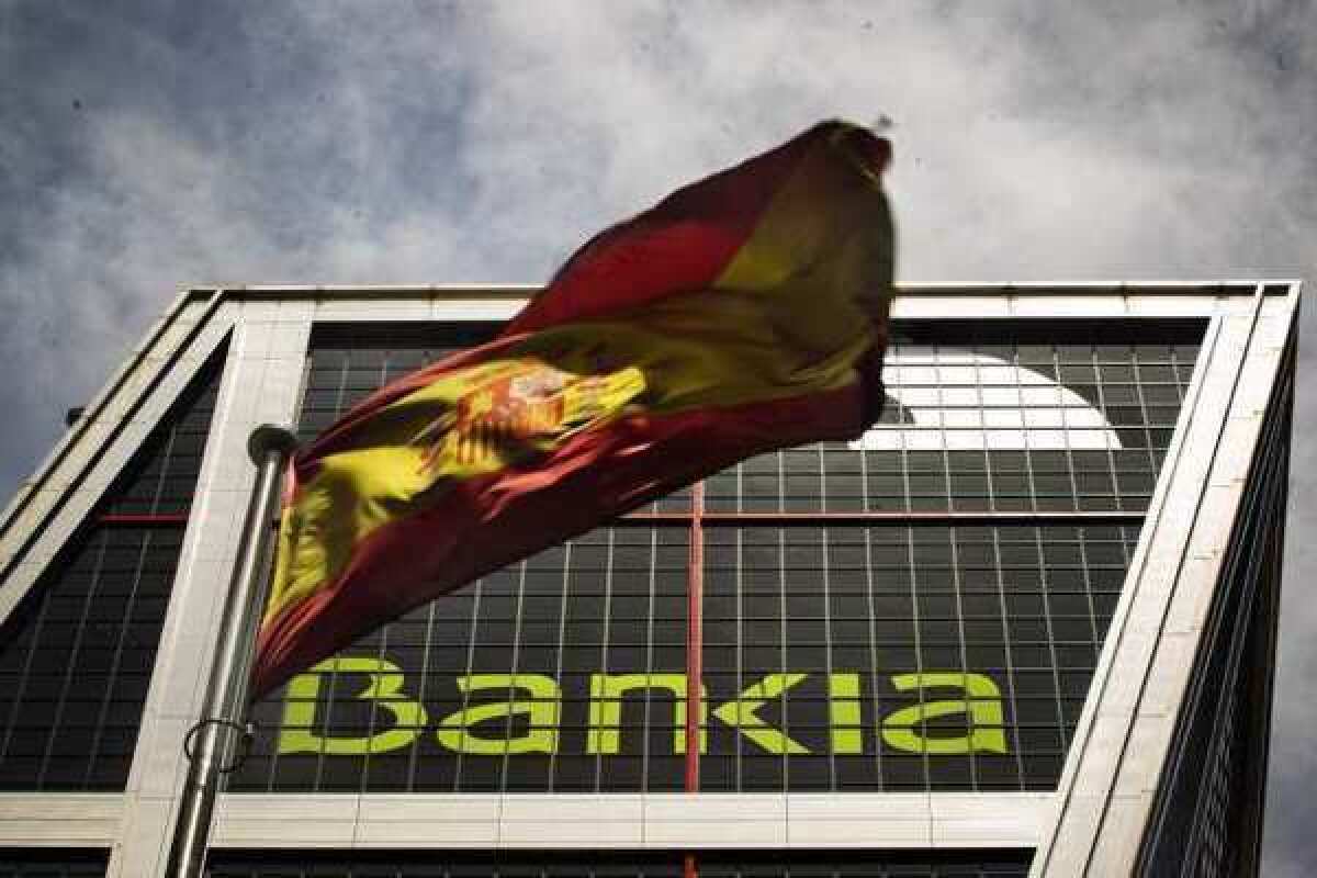 A Spanish flag flies in front of Bankia's headquarters in Madrid. Fitch slashed Spain's rating three notches Thursday.