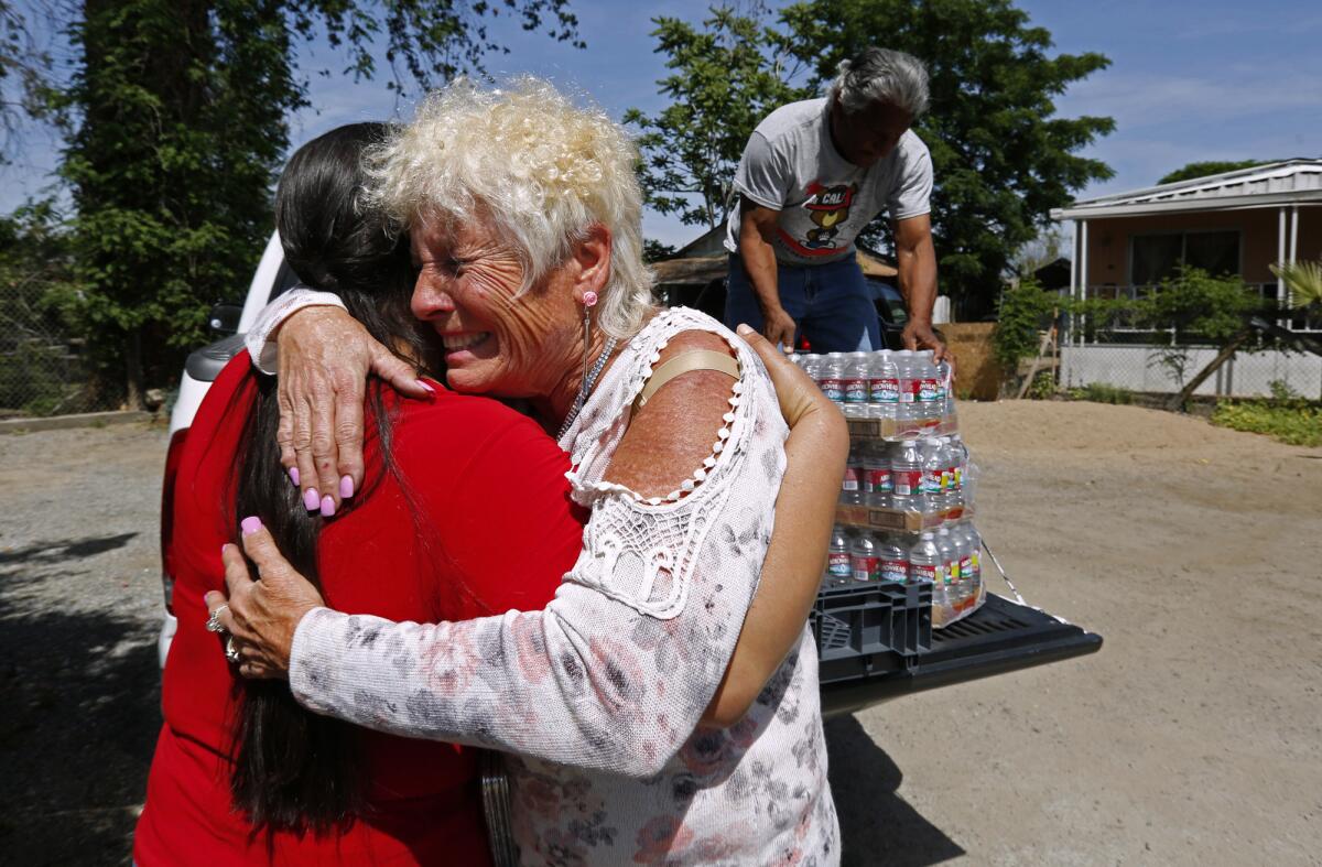 Donna Johnson, right, hugs Guillermina Andrade while delivering water with Ruben Perez to Andrade's home.