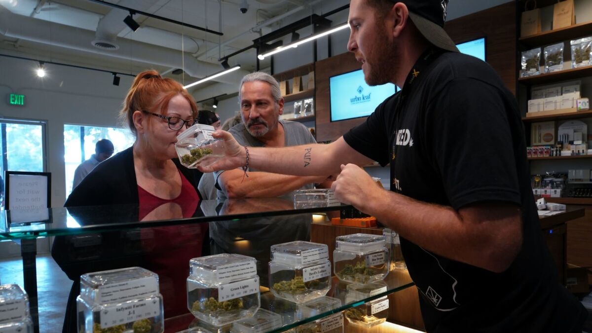 Michael Gladen and his wife Donna are assisted by budtender Jay Frentsos at Urbn Leaf with selecting from one of the many varieties of marijuana.