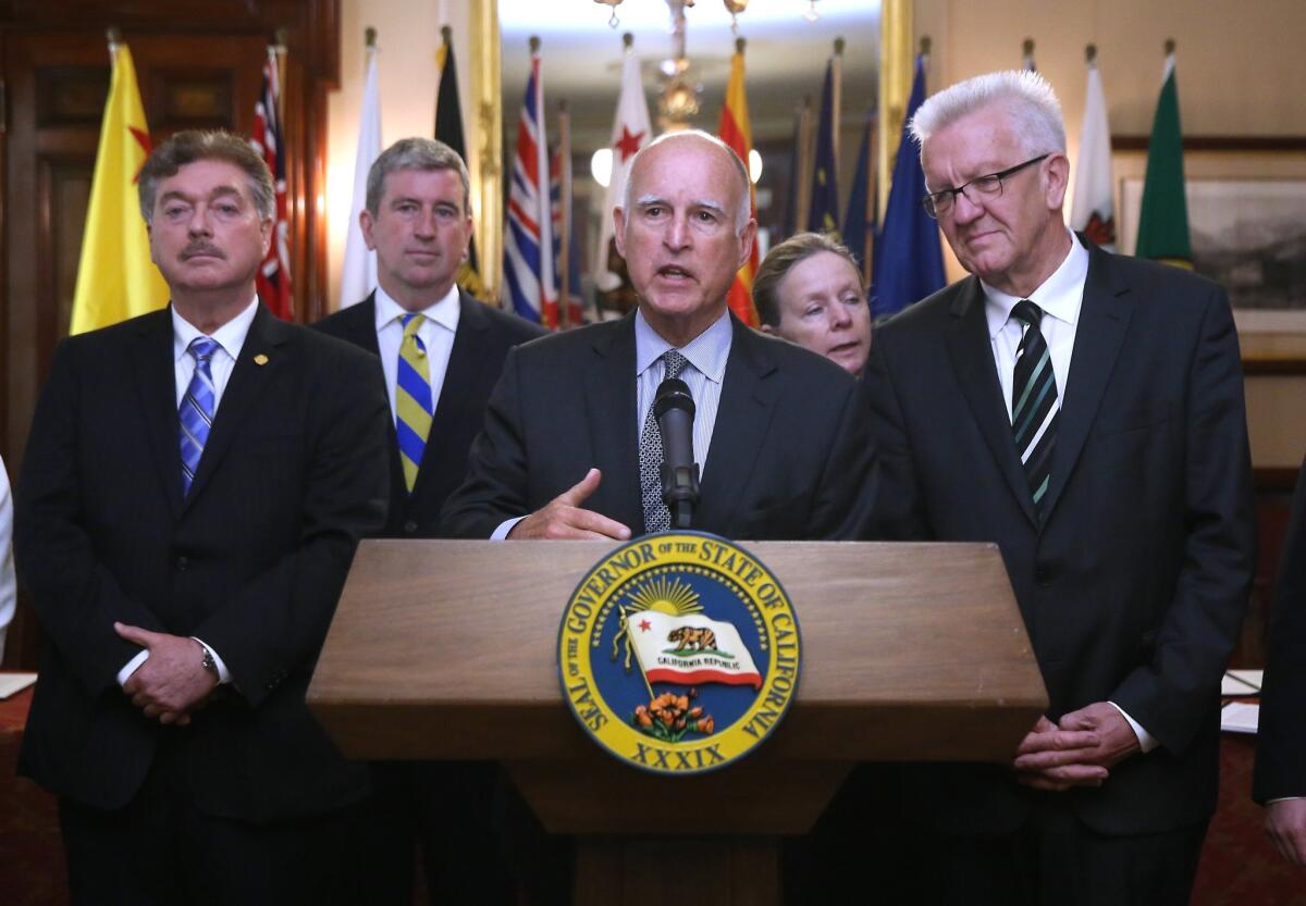 Gov. Jerry Brown, flanked by political leaders from other countries, discusses a new pact to address climate change during a news conference in Sacramento in May. He's in Toronto this week to push for more action on the issue.