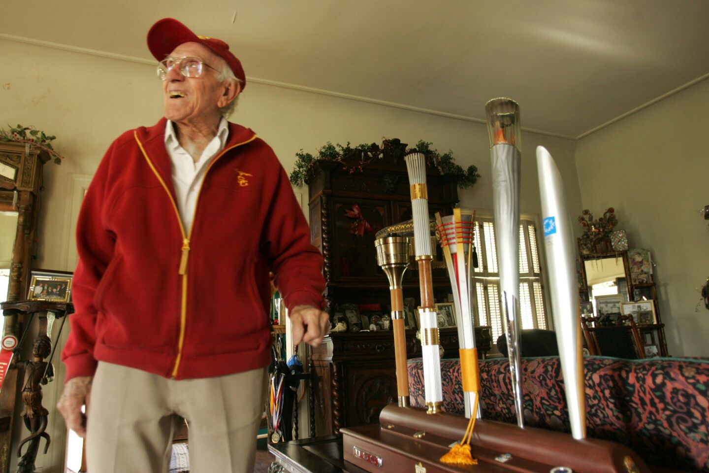 Louis Zamperini, 89, a former USC athlete and track-and-field Olympian, stands next to five Olympic torches he helped carry in five past Olympic games.