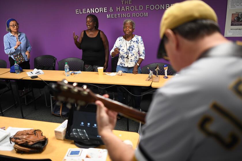 LOS ANGELES, CALIFORNIA JULY 27, 2019-Facilitator Jon Leonoudakis plays guitar as Alheimer's patient Dolores Jones, right, sings along with daughter Freda Cain and researcher KimiEgo during a meeting held by BasebALZ, a group that uses baseball to help stir the memories of patients with Alzheimer's disease, in Los Angeles. (Wally Skalij/Los Angeles Times)