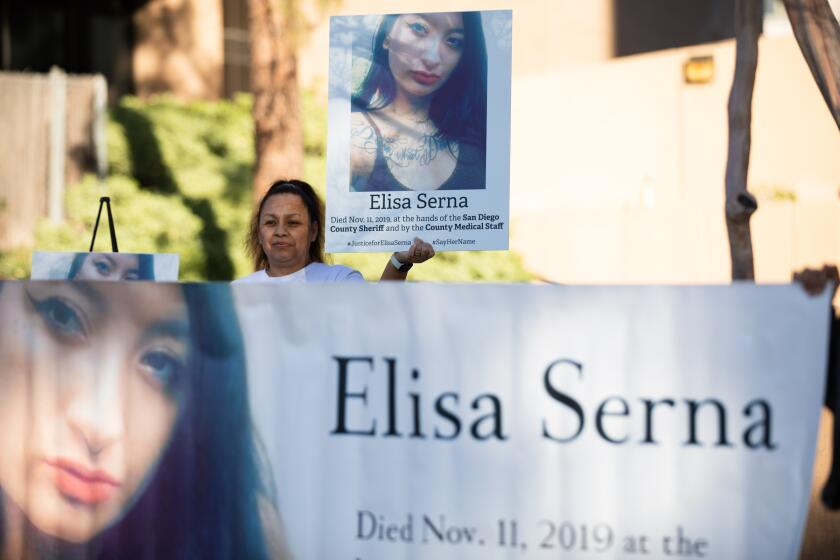 Paloma Serna, holds up a sign of her daughter, Elisa Serna, who died in jail in 2019, during a vigil and rally outside the El Cajon Courthouse on Monday, March 27, 2023. A court hearing for a jail nurse and jail doctor who have been charged with involuntary manslaughter in the death of Elisa Serna has been postponed to June 26.