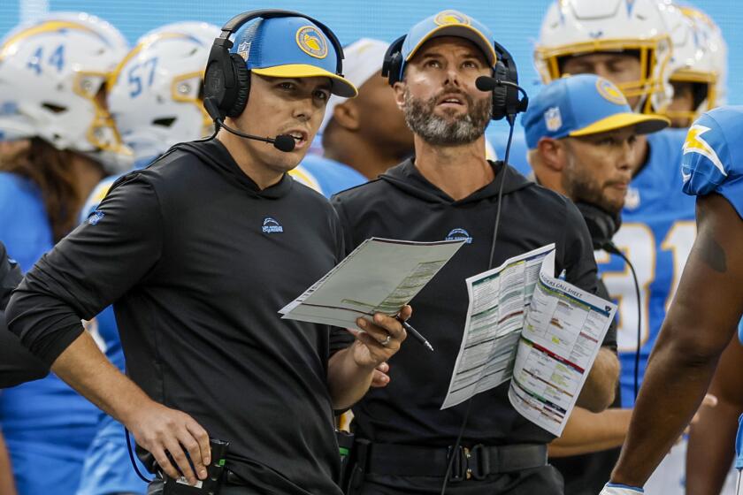 Chargers offensive coordinator Kellen Moore (left) and coach Brandon Staley compare notes.