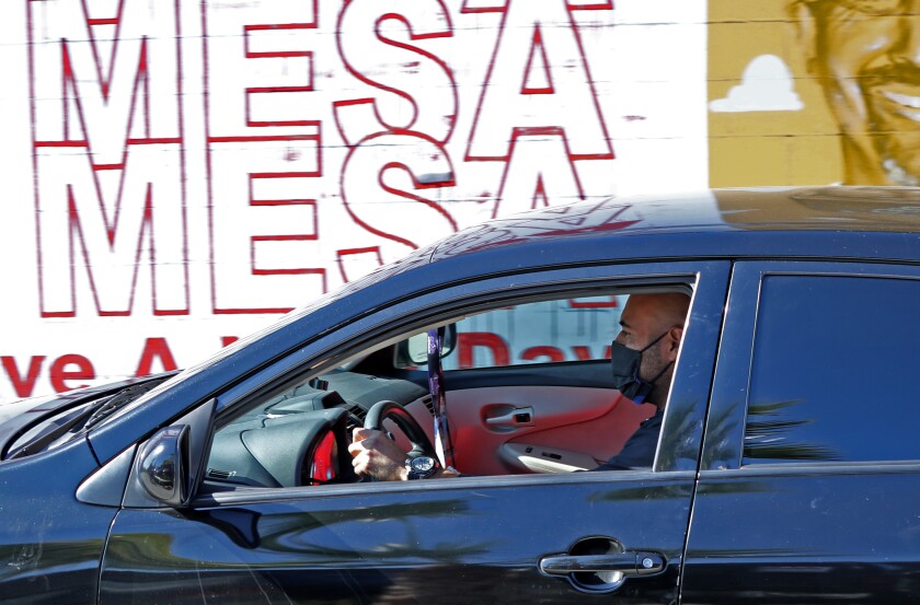 A man wears a face mask while driving on the 500 block of West 19th Street in Costa Mesa on Nov. 14.