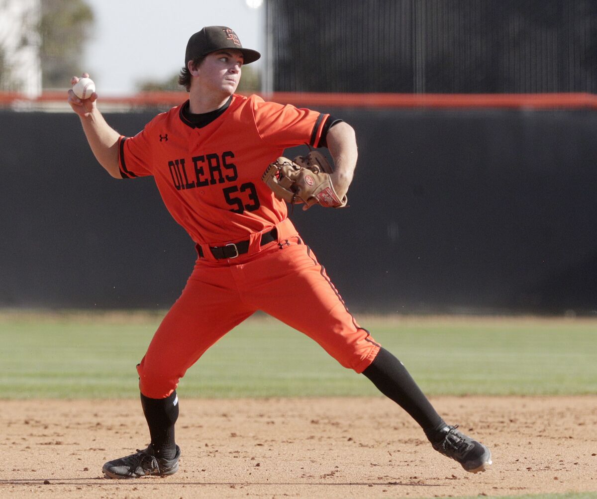 Huntington Beach third baseman Joe Yost throws out a Harvard-Westlake runner on Feb. 26. The Oilers, along with other local high school programs, have had their games suspended indefinitely due to the coronavirus.