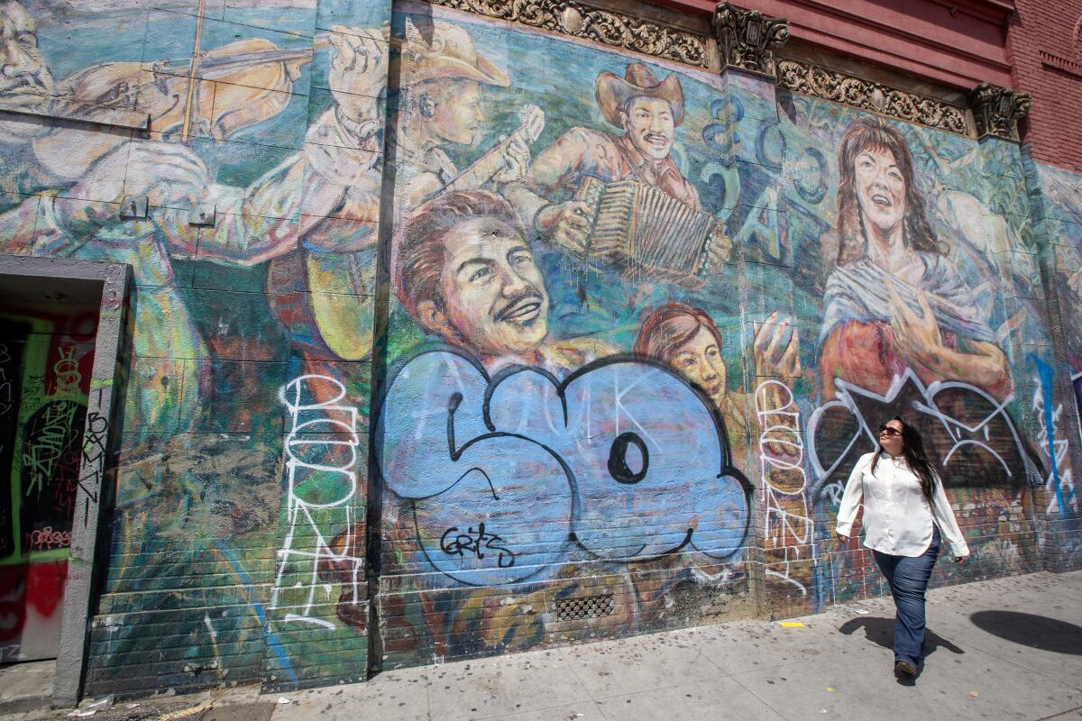 Assemblymember Wendy Carrillo walks near a mural that was defaced by graffiti.