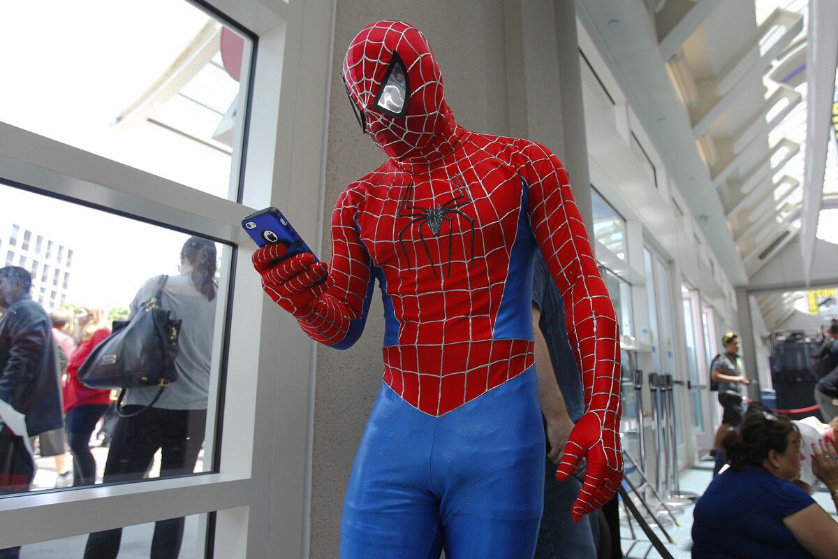 Tyson Brown as Spiderman checks his phone at Comic Con in 2014. (K.C. Alfred/Union-Tribune)