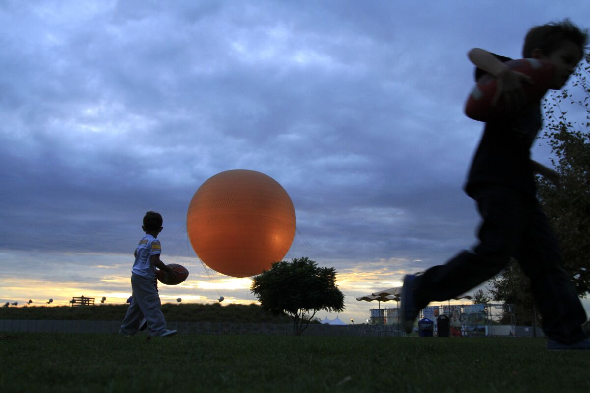 With the signature orange balloon in the background, children play as the sun sets at the Great Park in Irvine.