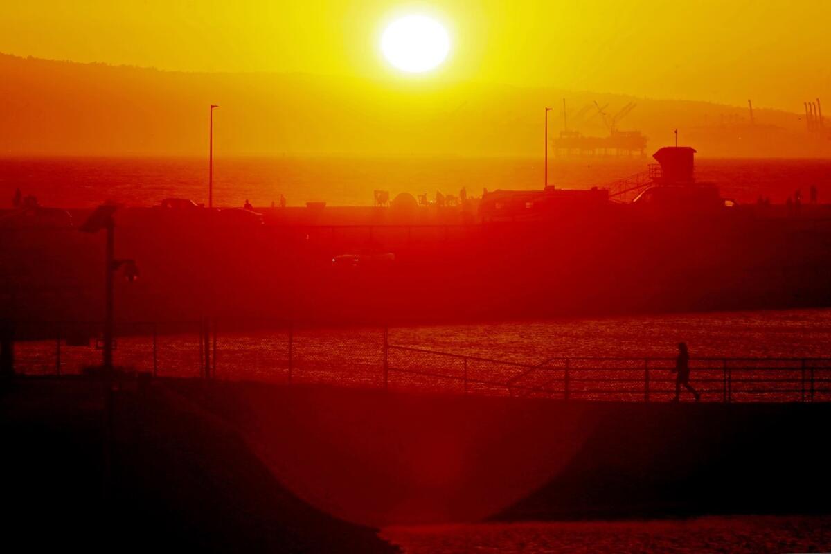 The sun glows over hazy hills and a beach.