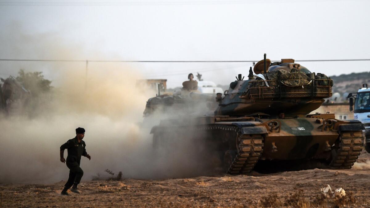 A Turkish soldier standing next to tanks near the Turkey-Syria border city of Karkamis.