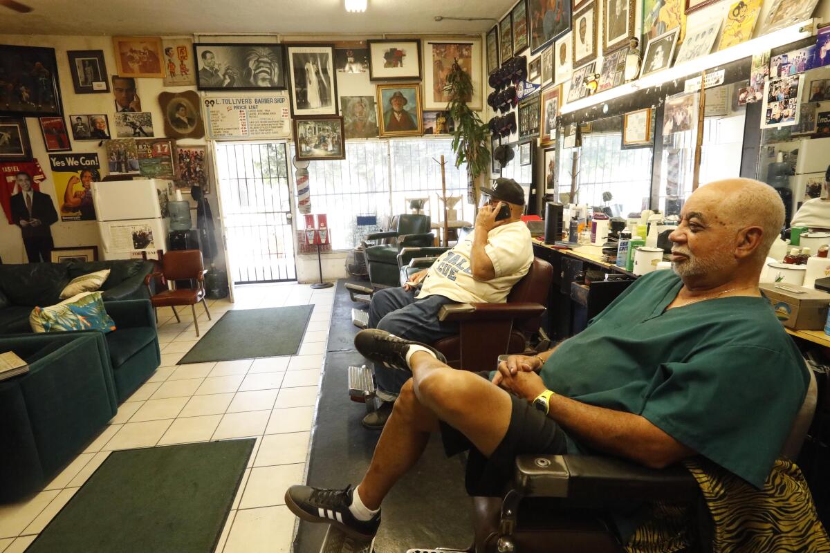 Lawrence Tolliver, , right, who waits for customers inside his famed Tolliver's Barber Shop in South Los Angeles in 2019. 