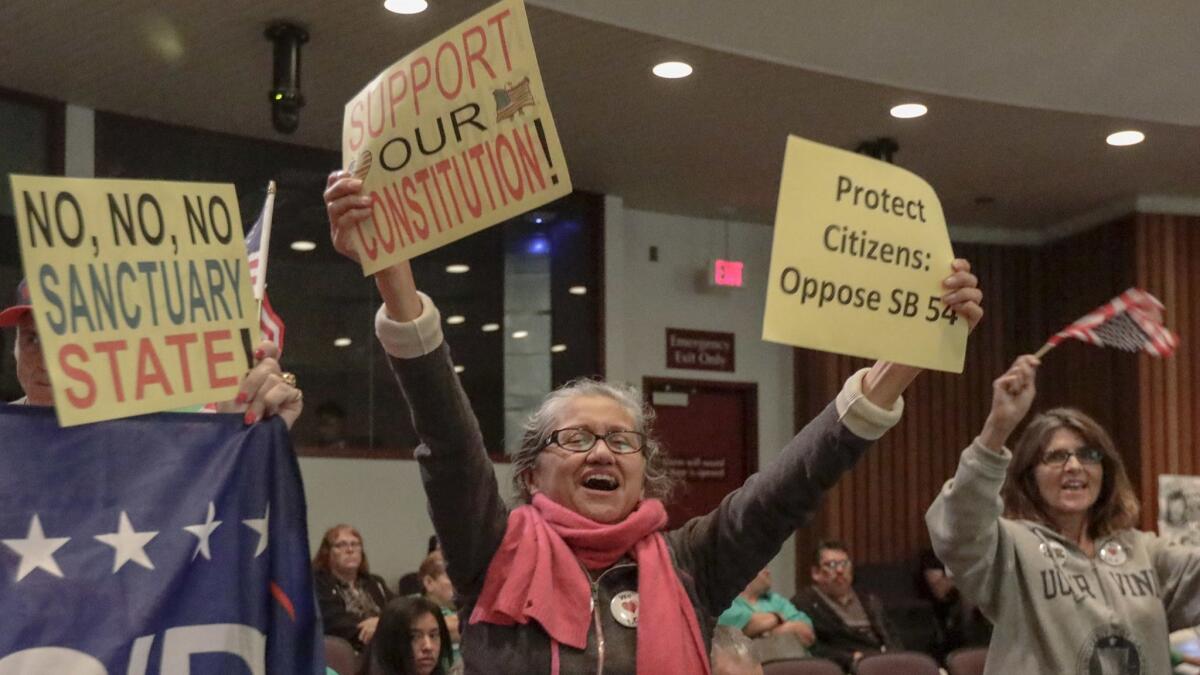 At the Orange County Board of Supervisors meeting, people opposing California's "sanctuary" law celebrate.