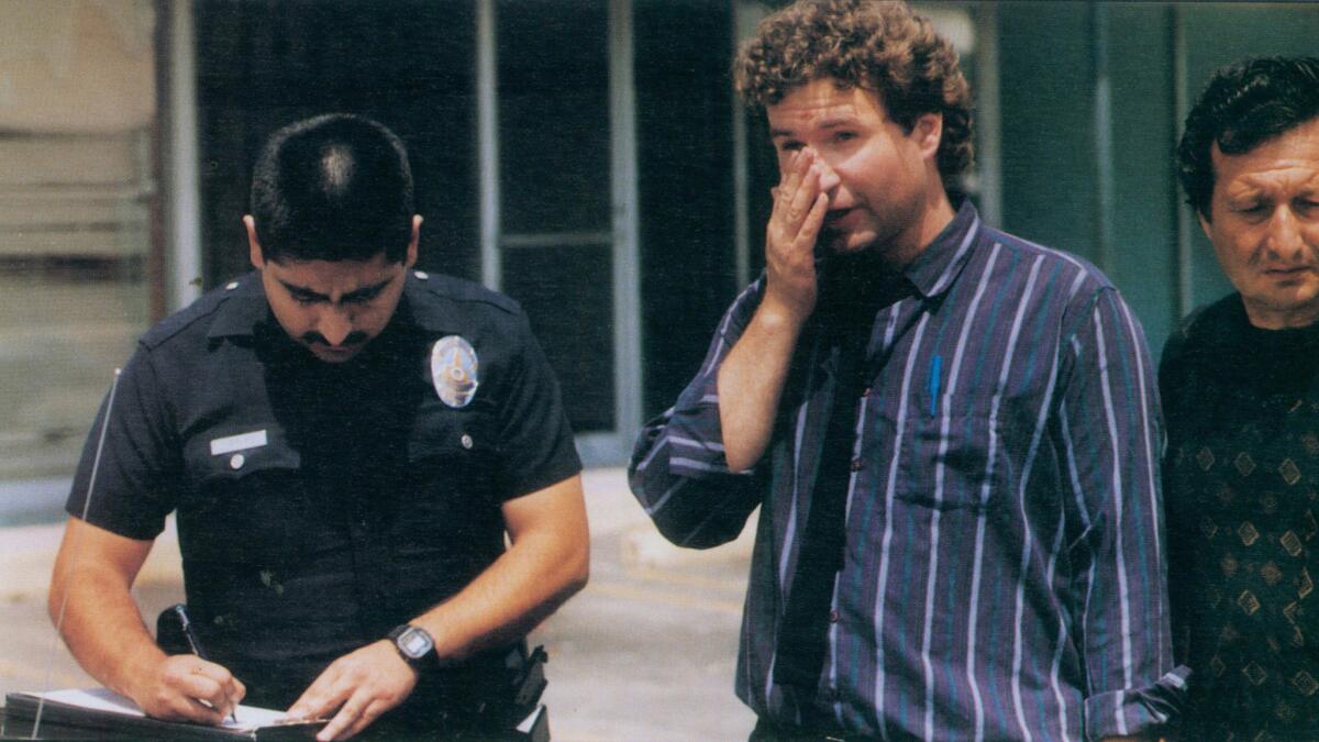 Los Angeles Times reporter Jim Herron Zamora, center, files a police report after being accosted and shot at by looters at a Panorama City delicatessen.