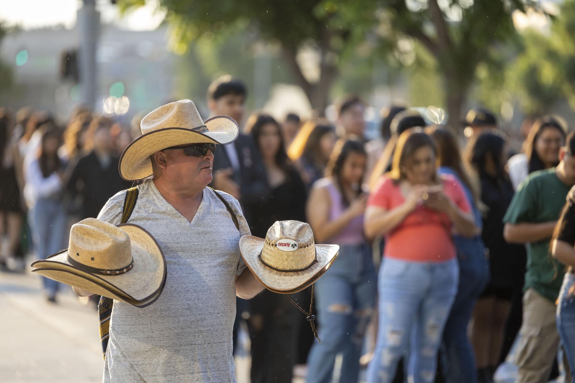 A hat seller walks along a line of people in a line.