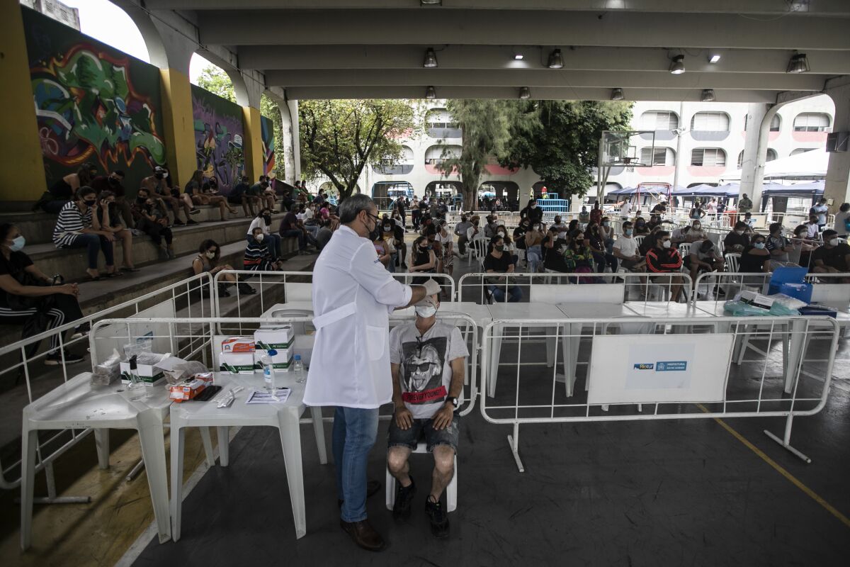 A healthcare worker takes a nasal sample for a COVID-19 test at a test site set up at a school in Rio de Janeiro, Brazil, Friday, Jan. 7, 2022. (AP Photo/Bruna Prado)